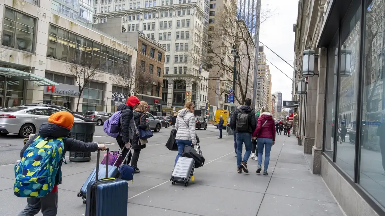 શહેરના ફૂટપાથ પર લગેજ સાથે લોકો મુસાફરી કરતા 2025- અમેરિકન પ્રવાસન ખર્ચ 2025