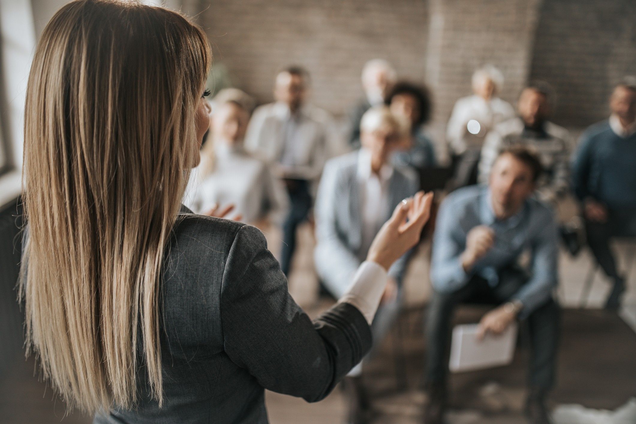 Female manager talking to large group of her colleagues on a business seminar.