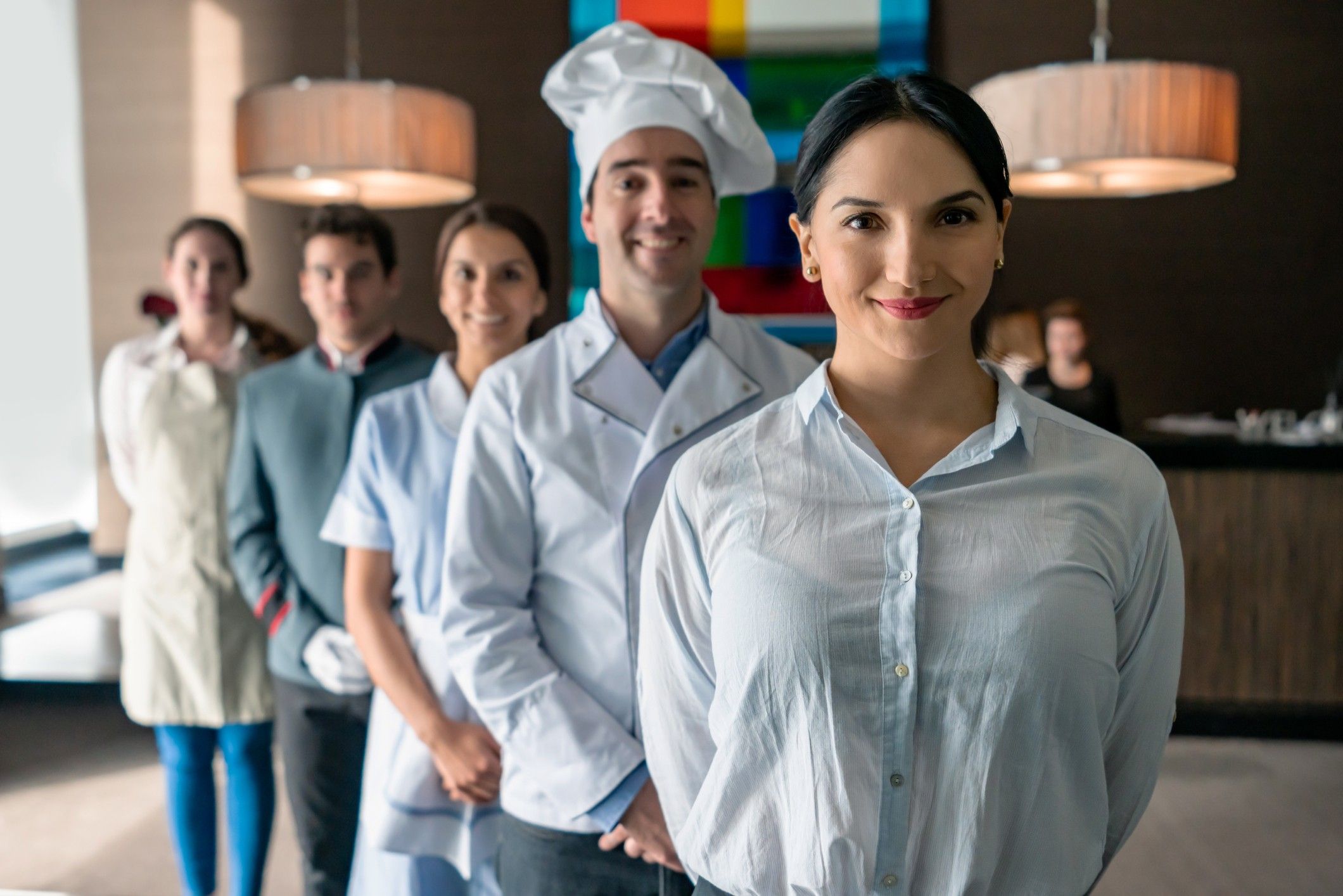 Professional hotel staff at a luxury hotel all facing camera smiling standing behind female manager USTA