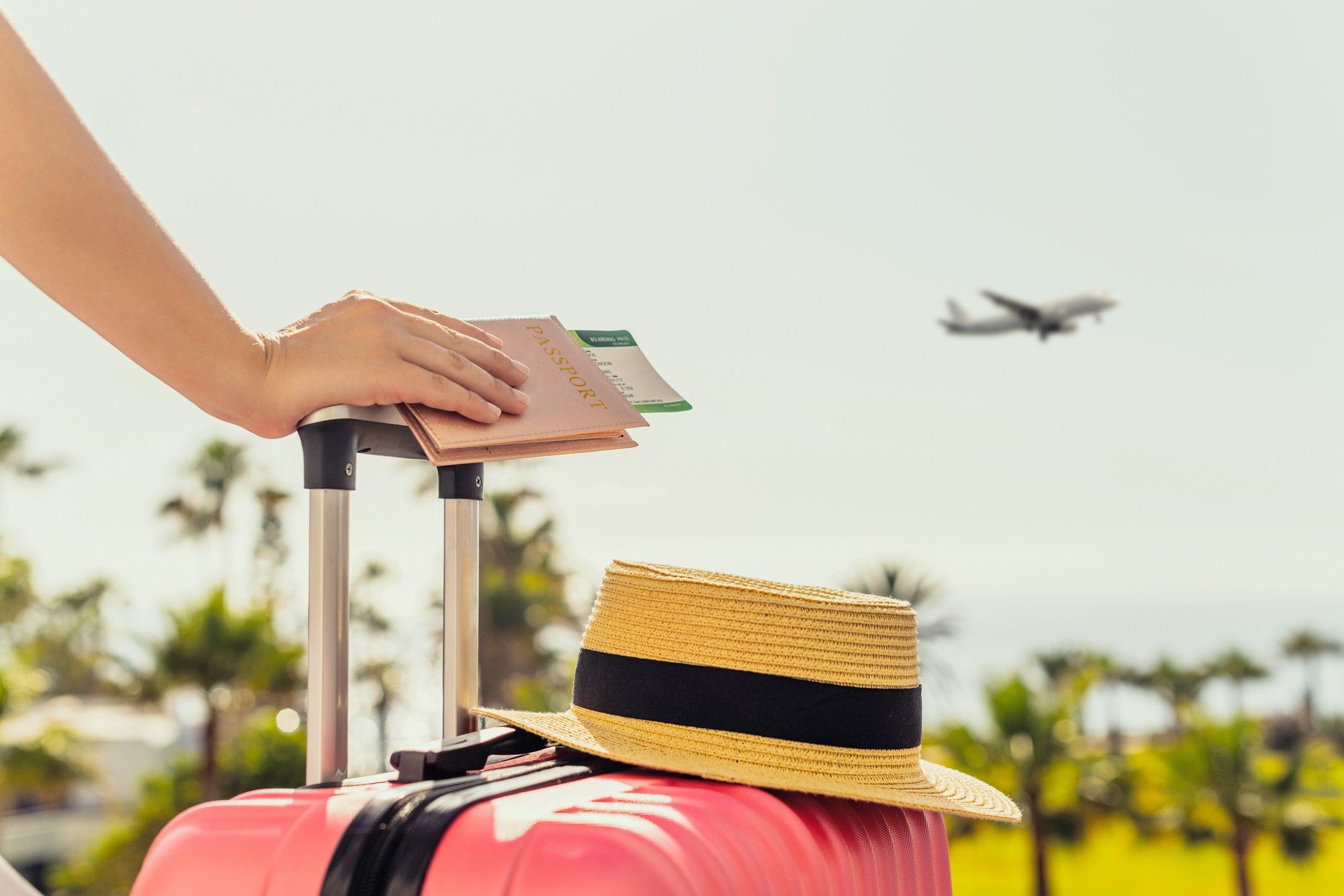 Woman with pink suitcase and passport with boarding pass standing on passengers ladder of airplane opposite sea with palm trees. Tourism concept U.S. hotel leisure travel revenue